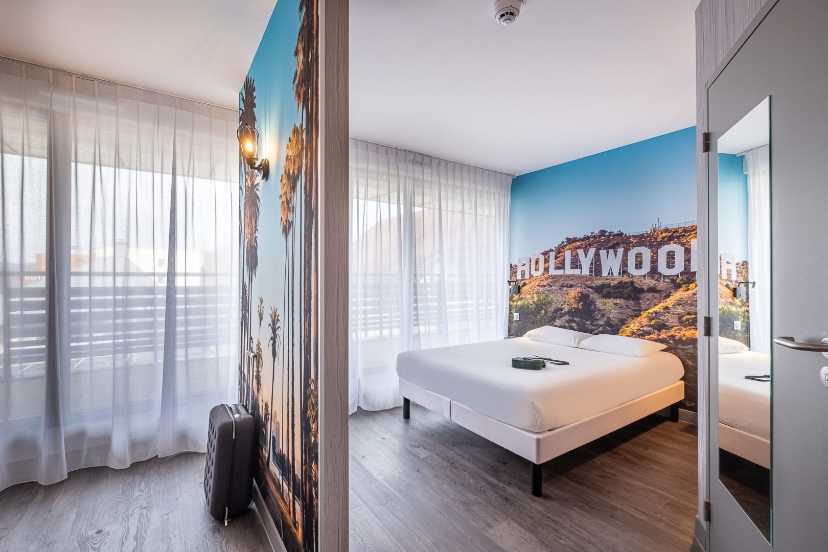 Chambre au style américain avec lit double, grandes baies vitrées et papier peint coloré au The Break Totem par ACP Hospitality.